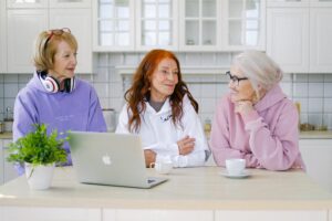 three older women chatting in a white kitchen